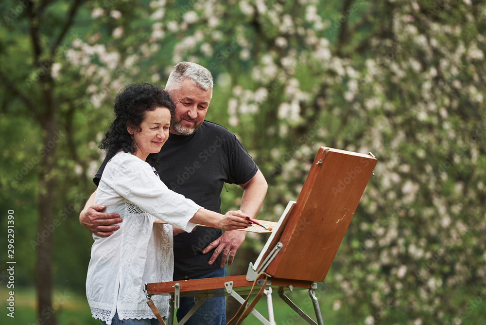 Take a look at this. Mature couple have leisure days and working on the paint together in the park Take a look at this. Mature couple have leisure days and working on the paint together in the park