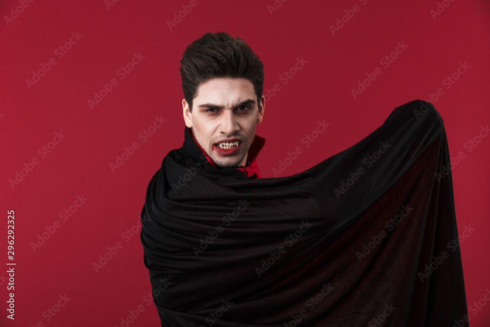 Image of vampire man in black halloween costume holding his cloak Image of vampire man in black halloween costume holding his cloak