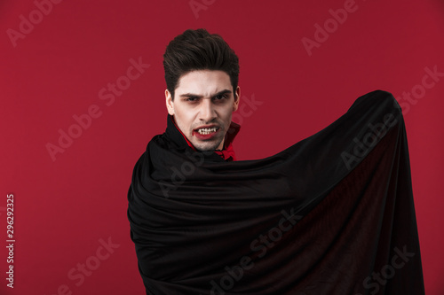 Obraz na plátně Image of vampire man in black halloween costume holding his cloak