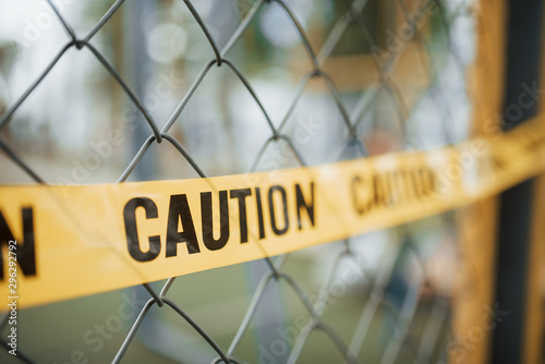 Do not enter. Yellow caution tape on the metal fence at daytime. Crime scene photo