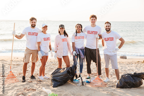 Image of happy multinational voluntary workers cleaning beach from plastic photo