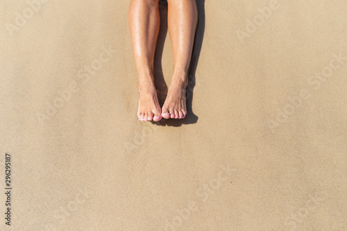 Top view of naked tanned women's feet in the sand on the beach, point of view of feet in the sand on the ocean, summer background-image, rest on the ocean beach, feet on the sea sand-image