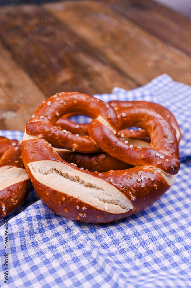 Bavarian pretzel decorated with a blue and white cloth on a rustic wooden board - Munich Oktoberfest. Background and free space for text. Traditional pastries for the festival. Close-up. Bavarian pretzel decorated with a blue and white cloth on a rustic wooden board - Munich Oktoberfest. Background and free space for text. Traditional pastries for the festival. Close-up.