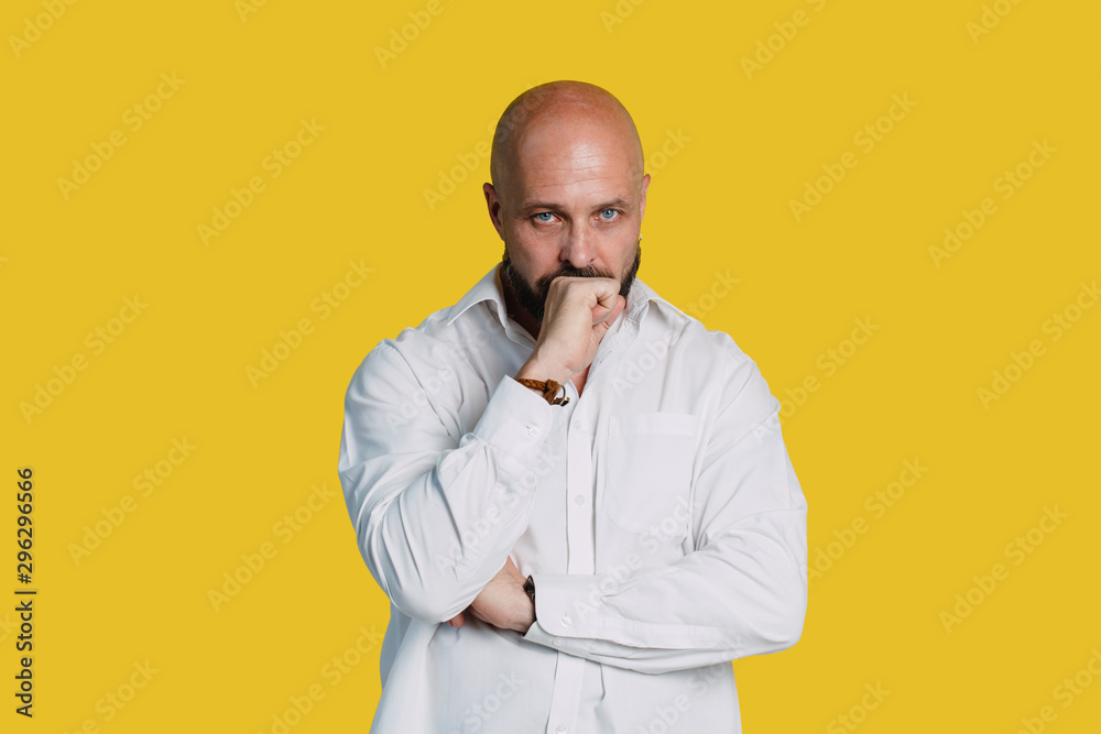 Handsome serious middle aged man meditate on yellow background with copy space. Handsome serious middle aged man meditate on yellow background with copy space.