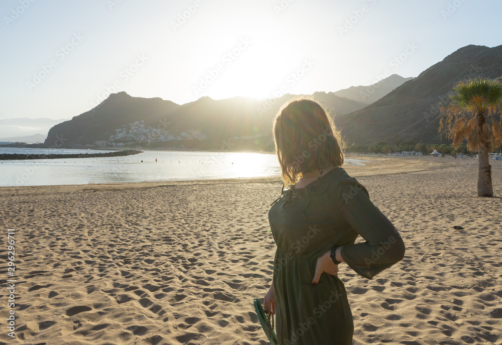 Spiritual adolescent in green dress admire the sunset and the sea town on a hill in Tenerife. Blonde romantic woman look the paradise in her vacation in calm Spiritual adolescent in green dress admire the sunset and the sea town on a hill in Tenerife. Blonde romantic woman look the paradise in her vacation in calm