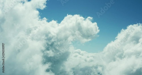 Aerial drone view flying forward through a sunny cloudscape mid day with blue skies, view from the front of an airplane, travel airlines freedom concept, cloudscape background