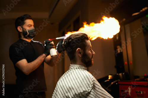 Professional barber doing haircut with fire treatment