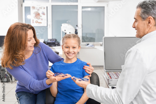 Girl looking at camera while doctor offering new glasses