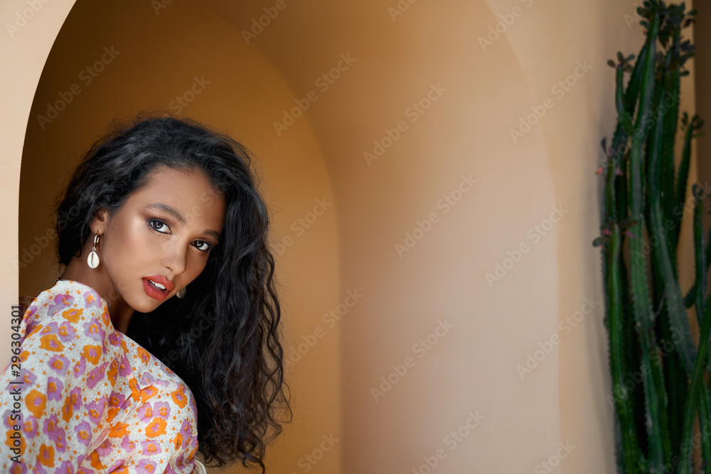 Fototapeta premium Close up of gorgeous girl in colored blouse leaning on wall
