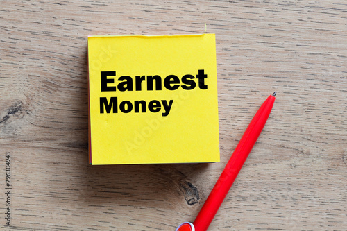 фотографія Earnest money text written in a sticky note. View from above