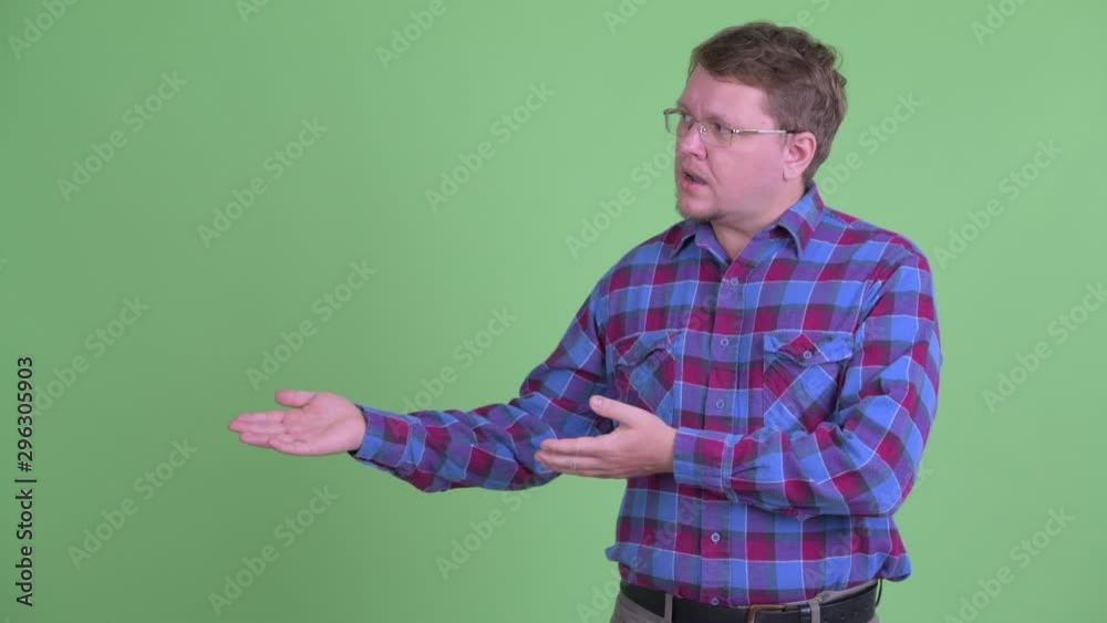 Happy overweight bearded hipster man talking while showing something Happy overweight bearded hipster man talking while showing something