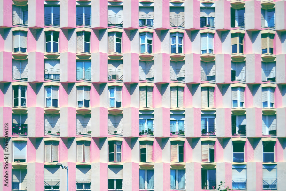 Mediterranean facade in Barcelona with pink wall and geometric balconies and windows in a textured distribution. Architecture background.