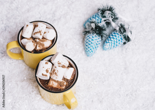 Mugs with marshmallows near Christmas toys between snow © Freepik