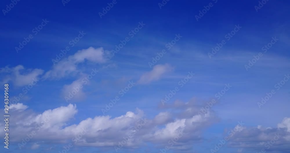 Panning view of fluffy white clouds against a vivid blue sky on a sunny day in Indonesia Panning view of fluffy white clouds against a vivid blue sky on a sunny day in Indonesia