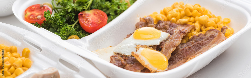 panoramic shot of eco package with corn, meat, fried eggs and salad on white background