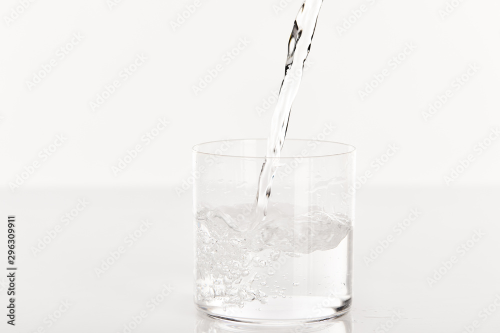 clear fresh water pouring into glass isolated on white clear fresh water pouring into glass isolated on white