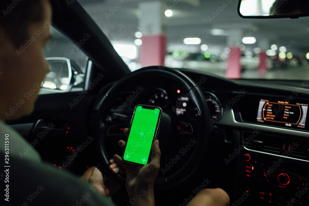 Naklejka premium Man driving holding smartphone in car