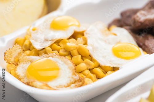 selective focus of eco package with corn and fried eggs on white background