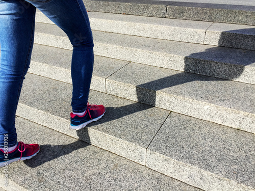 Young sport woman running up on stone stairs with sun spot background. Healthy lifestyle, workout and diet concept.