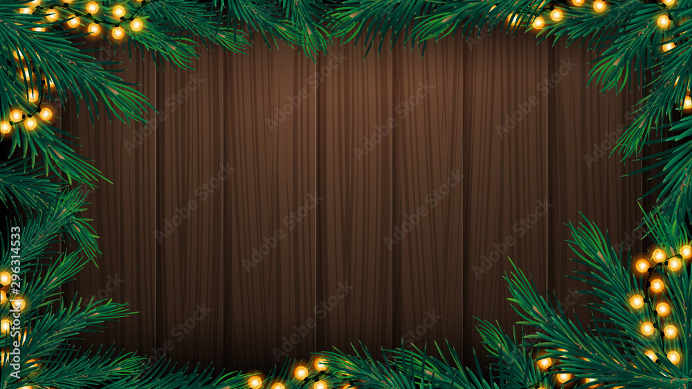 Wooden wall with frame made of Christmas tree branches and garland. Wooden Christmas background for your arts Wooden wall with frame made of Christmas tree branches and garland. Wooden Christmas background for your arts
