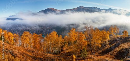 Panoramic autumn view, Altai nature, Russia. Fog above the mountain valley, the village below.