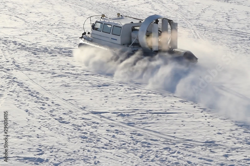 Hovercraft crosses frozen river on Sunny winter day