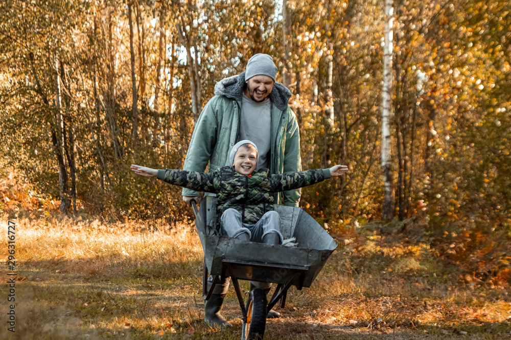 Dad spends time with his son, a happy little boy pushed by a dad. Active outdoor games for children in the fall. Dad spends time with his son, a happy little boy pushed by a dad. Active outdoor games for children in the fall.