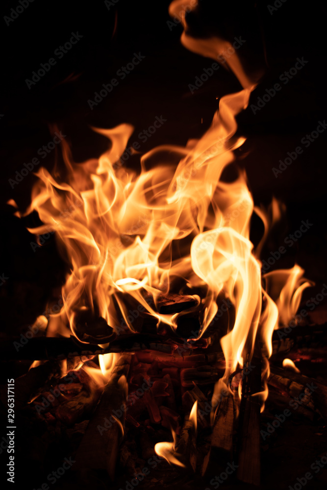 Burning wood at night. Campfire at touristic camp in nature in mountains. Flame and fire sparks on dark abstract background. Burning wood at night. Campfire at touristic camp in nature in mountains. Flame and fire sparks on dark abstract background.