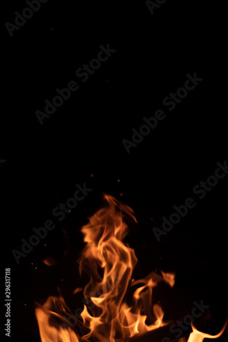 Burning wood at night. Campfire at touristic camp in nature in mountains. Flame and fire sparks on dark abstract background.