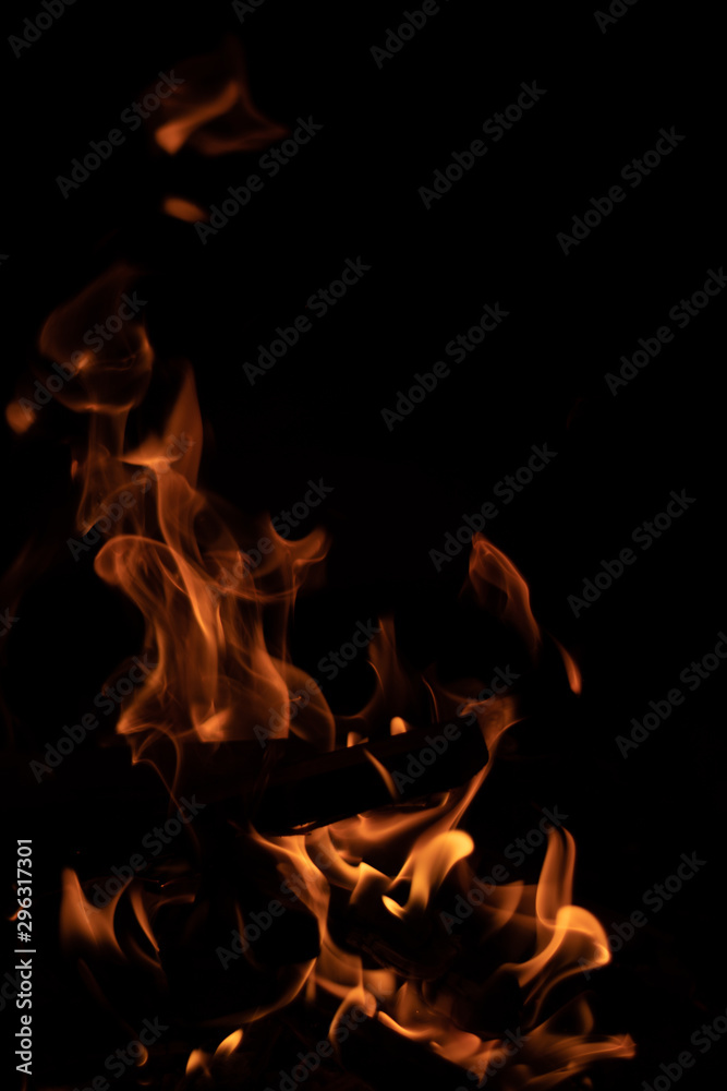 Burning wood at night. Campfire at touristic camp in nature in mountains. Flame and fire sparks on dark abstract background. Burning wood at night. Campfire at touristic camp in nature in mountains. Flame and fire sparks on dark abstract background.