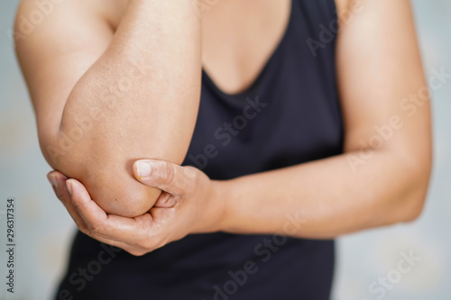 Asian middle-aged lady woman patient touch and feel pain her elbow and arm : healthy medical concept..