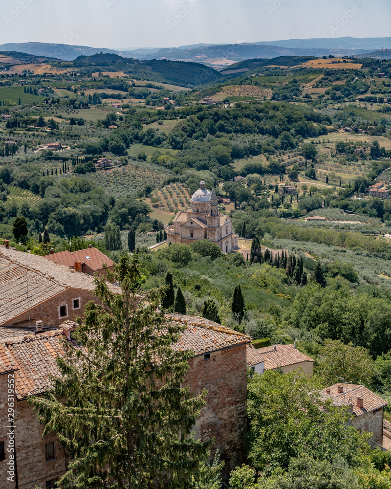 A church In Montalcino Tuscany With Trees, Vineyards, Crops And Hills in the Background