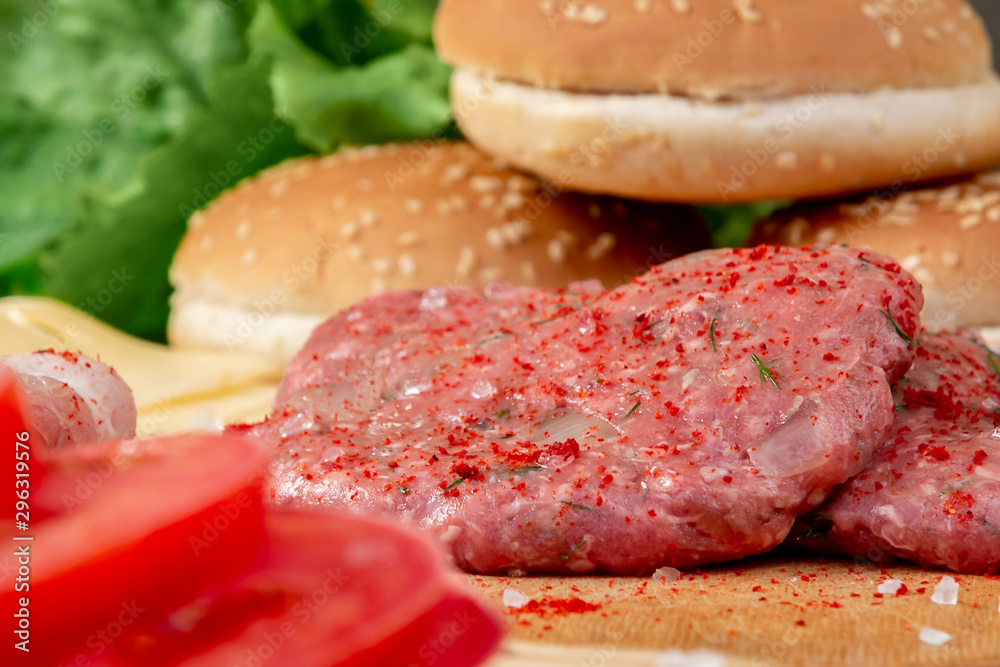 Process of cooking homemade burgers, meatballs, tomatoes, cheese and other ingredients on a wooden background, close up Process of cooking homemade burgers, meatballs, tomatoes, cheese and other ingredients on a wooden background, close up
