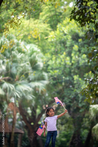 Malaysia Girl waving a Malaysia Flag. Outdoor Setting.
