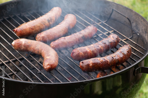 Cooking meat sausages on a round grill outdoors