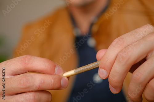 Young guy makes cigarette with hand rolling tobacco