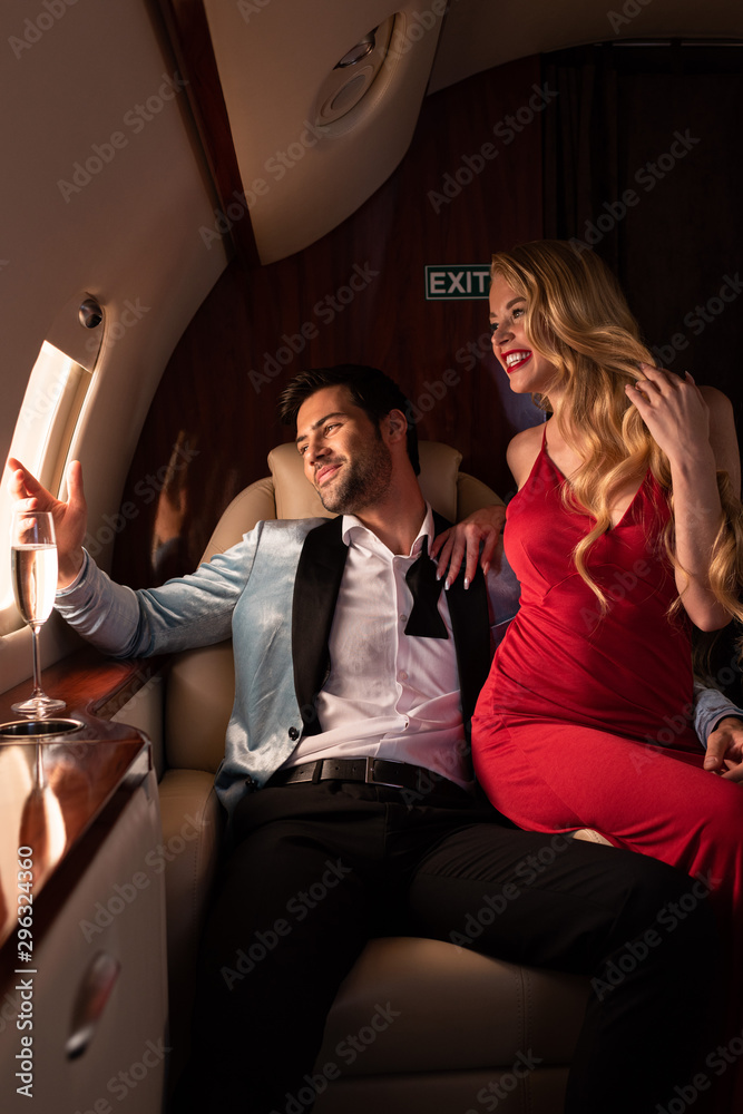 attractive woman and man with champagne sitting in airplane attractive woman and man with champagne sitting in airplane