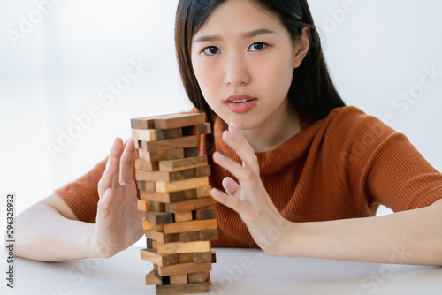 worry stress asian smart woman try to built and protect wooden stack tower risk management strategy ideas concept