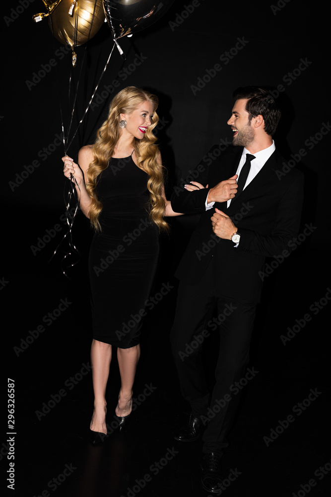 beautiful cheerful couple with golden balloons on party isolated on black