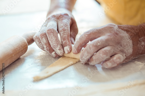 Fototapeta Female hands rolling dough into rolls