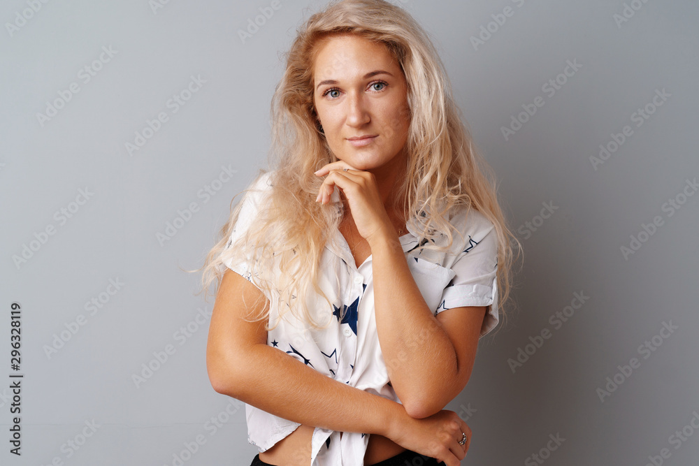 Beautiful blonde woman with curly hair posing over a grey background. Beautiful blonde woman with curly hair posing over a grey background.