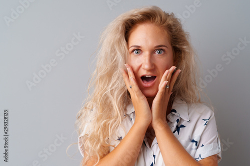 Young beautiful woman portrait being excited and amazed over gray background.