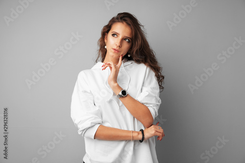 Image of thinking young woman standing over a gray background