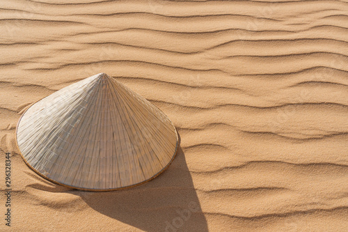 Fototapeta Naklejka Na Ścianę i Meble -  Non la hat, Vietnamese style put on the sand at white sand dune desert, copy space.