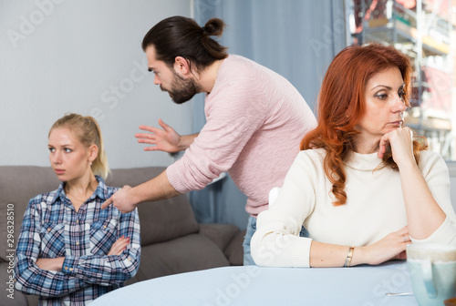 Mature woman sitting, man and girl having conflict on background