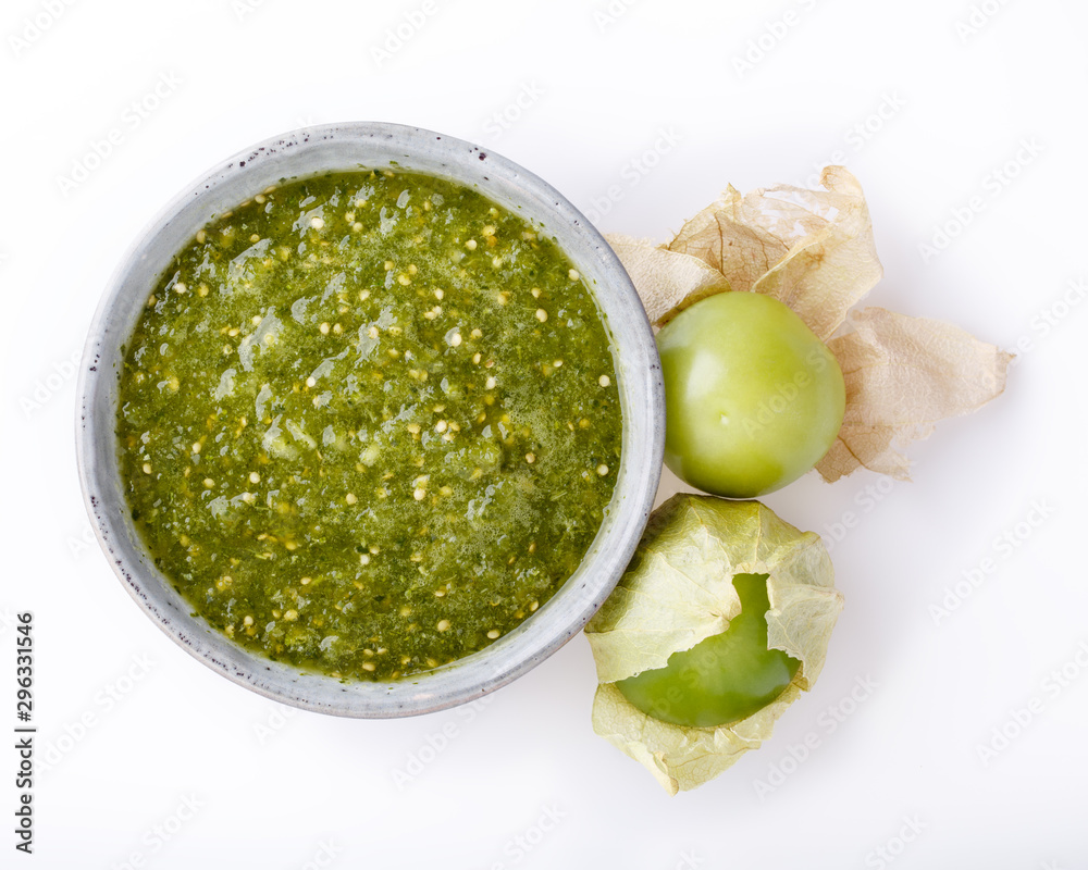Tomatillo salsa verde. Bowl of spicy green sauce on white table, mexican cuisine. Top view. - obrazy, fototapety, plakaty 