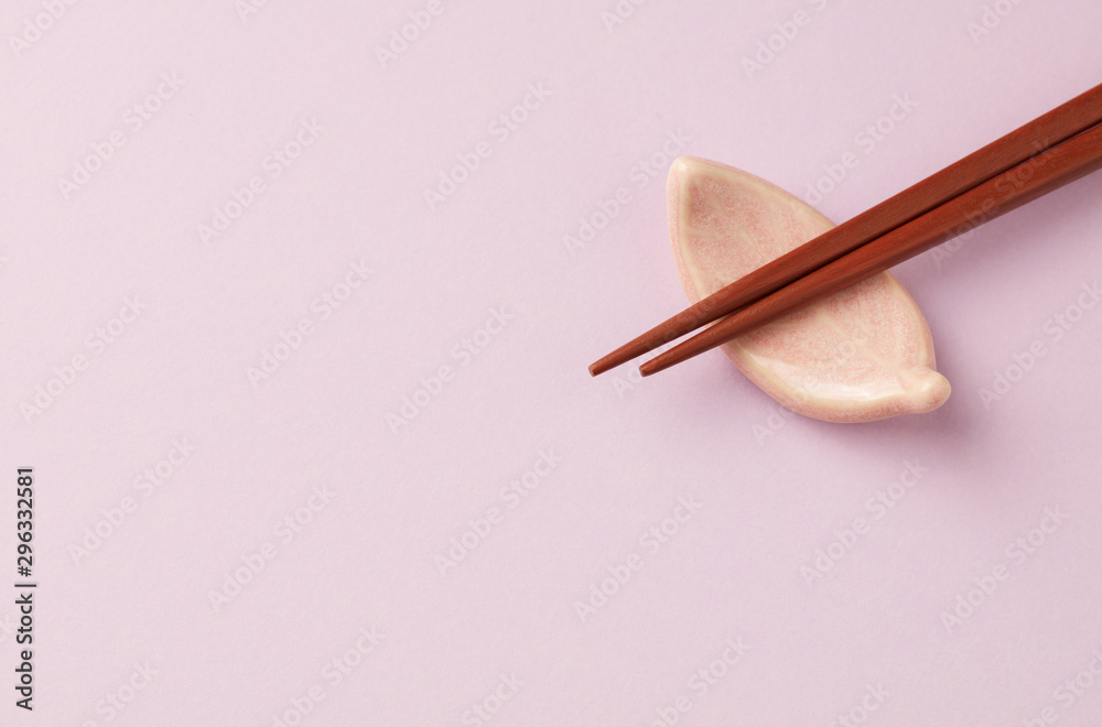 Wooden chopsticks and chopstick rest on bright paper background. Close up. Copy space. Wooden chopsticks and chopstick rest on bright paper background. Close up. Copy space.