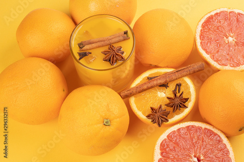 Fototapeta Naklejka Na Ścianę i Meble -  Fresh orange cinnamon star anise clove spice juice in glass on white yellow background