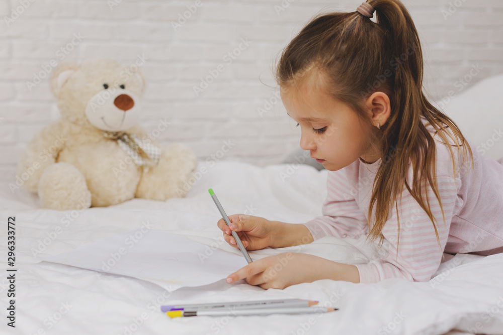 cute little girl drawing pictures while lying on bed. Kid painting at home cute little girl drawing pictures while lying on bed. Kid painting at home