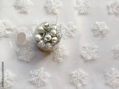 Box with christmas silver balls across white snowflakes background. Copy space. Christmas card. Christmas concept